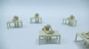 Plastic figures resembling humans who sit at tables in front of laptops. the lack of background makes their environment look bleak.