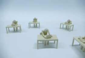 Plastic figures resembling humans who sit at tables in front of laptops. the lack of background makes their environment look bleak.
